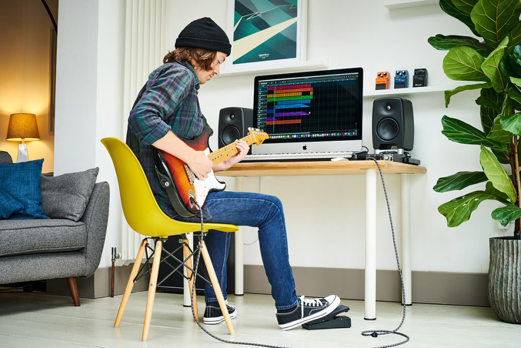 Guitarist playing EV-1-WL in front of computer