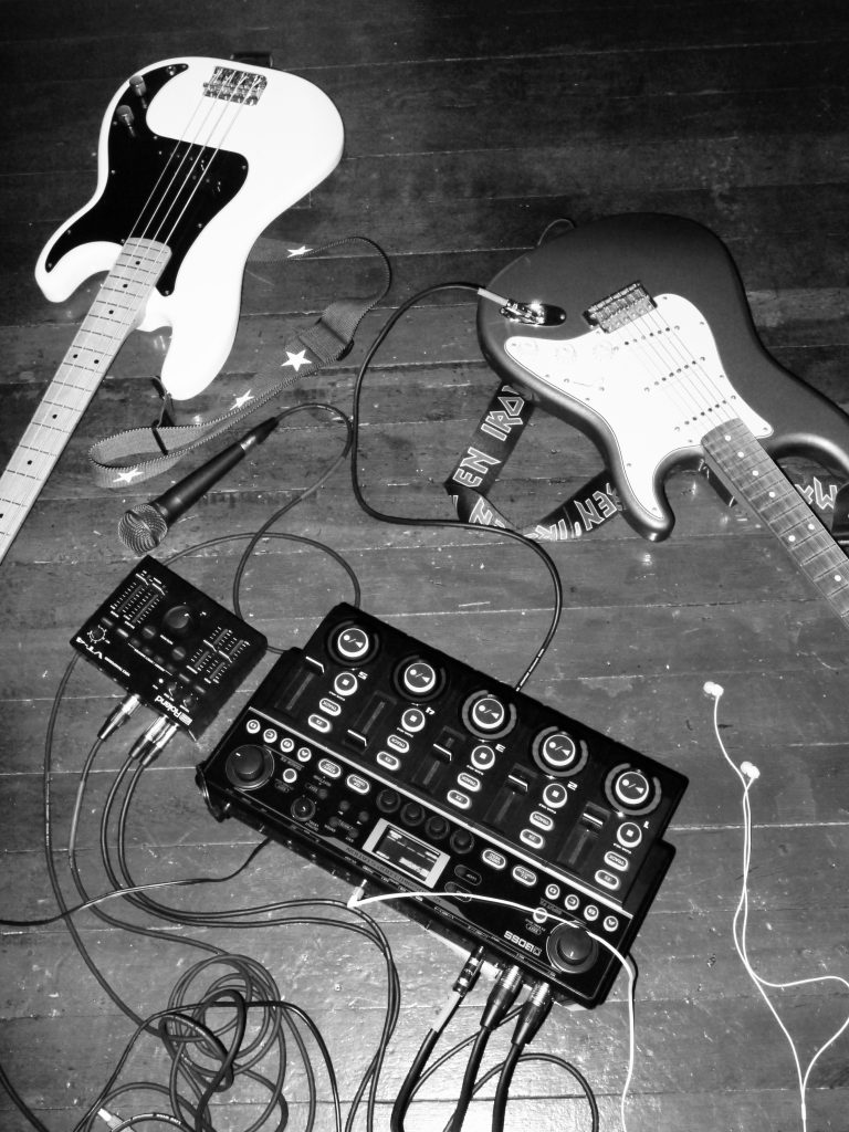 Oxis' rig comprising the BOSS RC-505mkII Loop Station, Roland VT-4 Voice Transformer, electric guitar, and electric bass